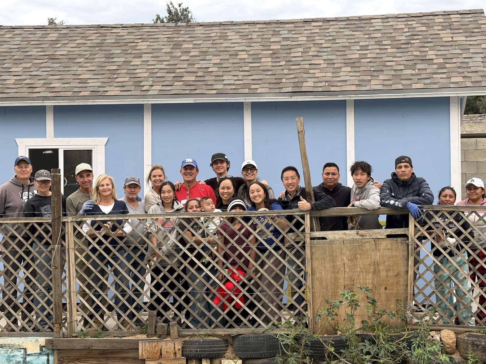 Volunteers and a Tecate family gathered in front of a newly finished home