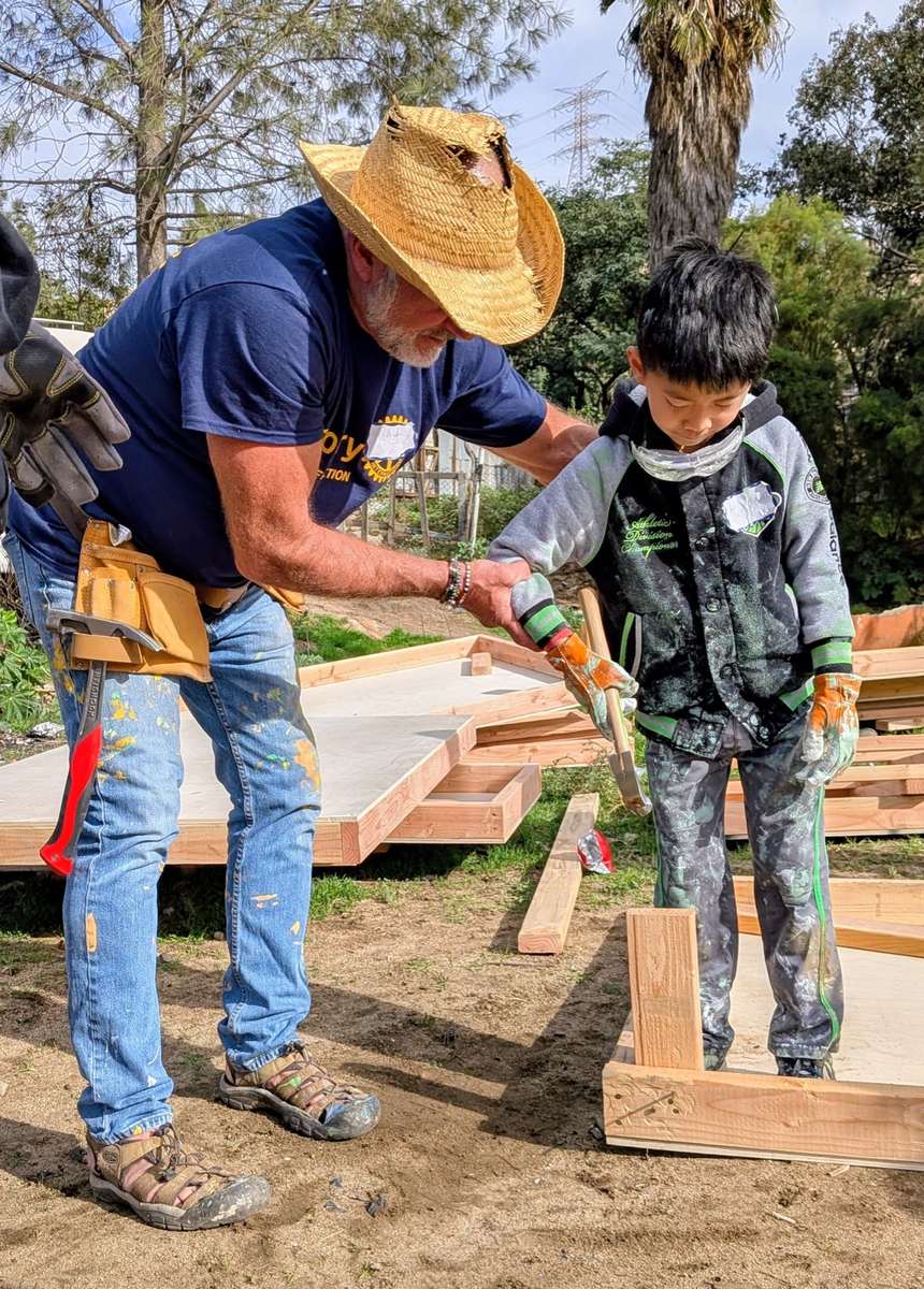 A volunteer helping a Tecate boy use a drill