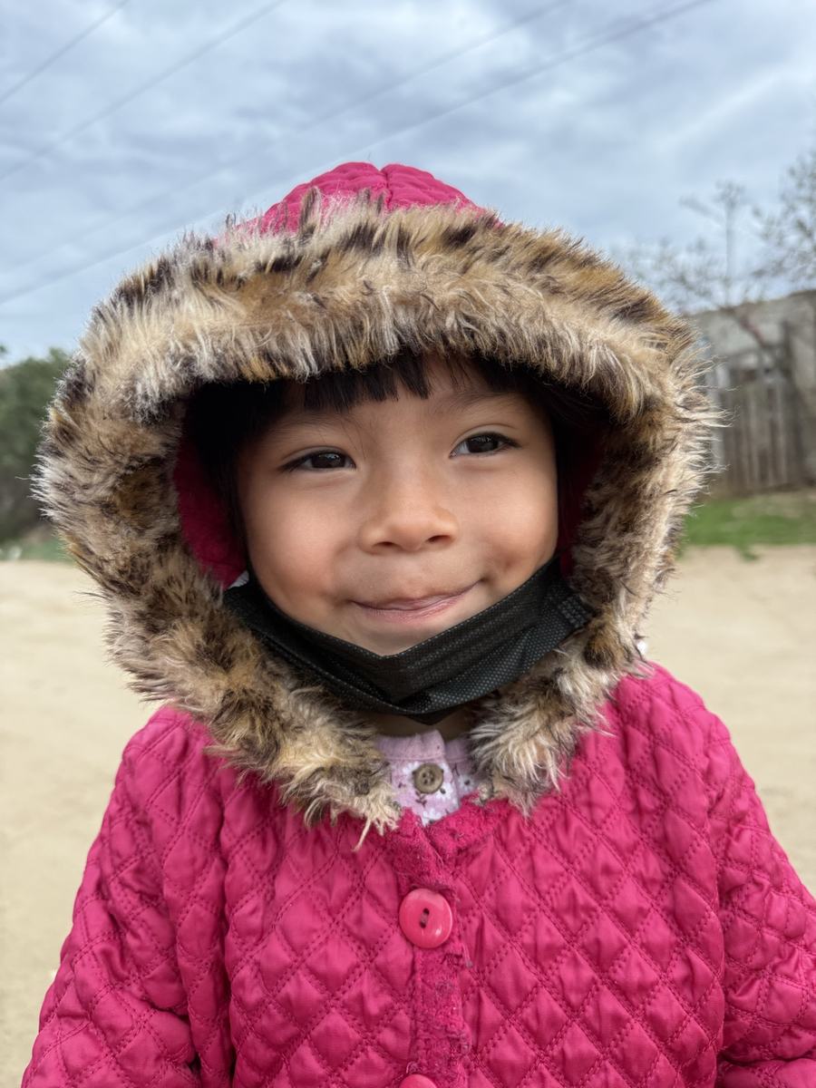 A girl in a pink fur-trimmed hood smiling