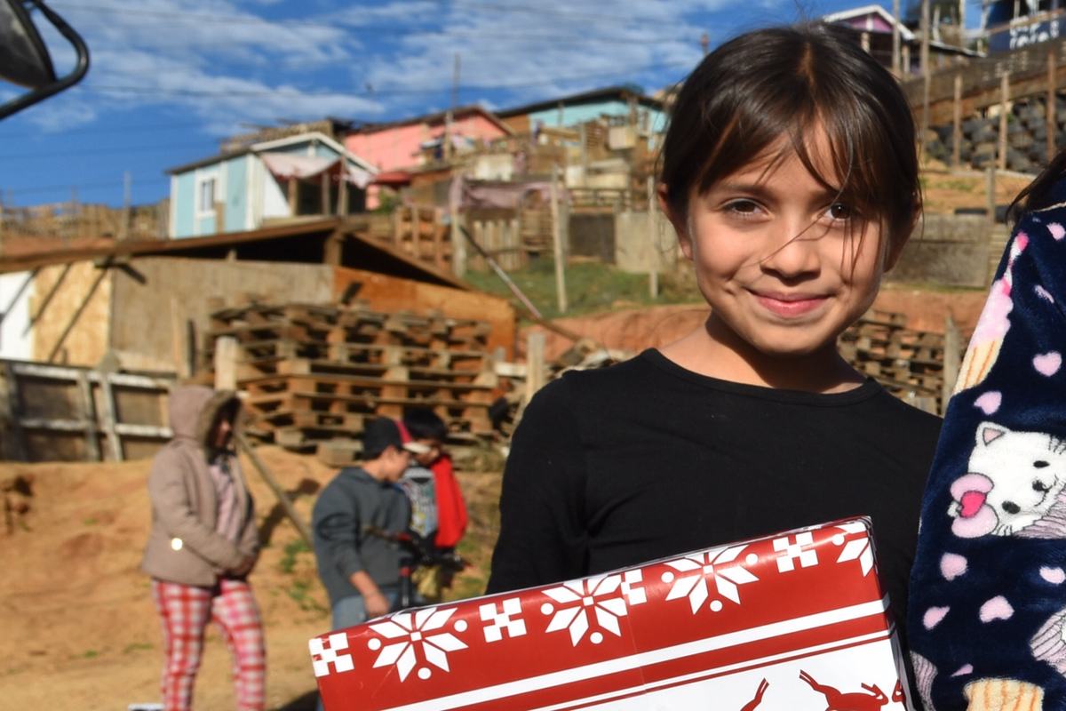 A girl smiling in front of stacked lumber