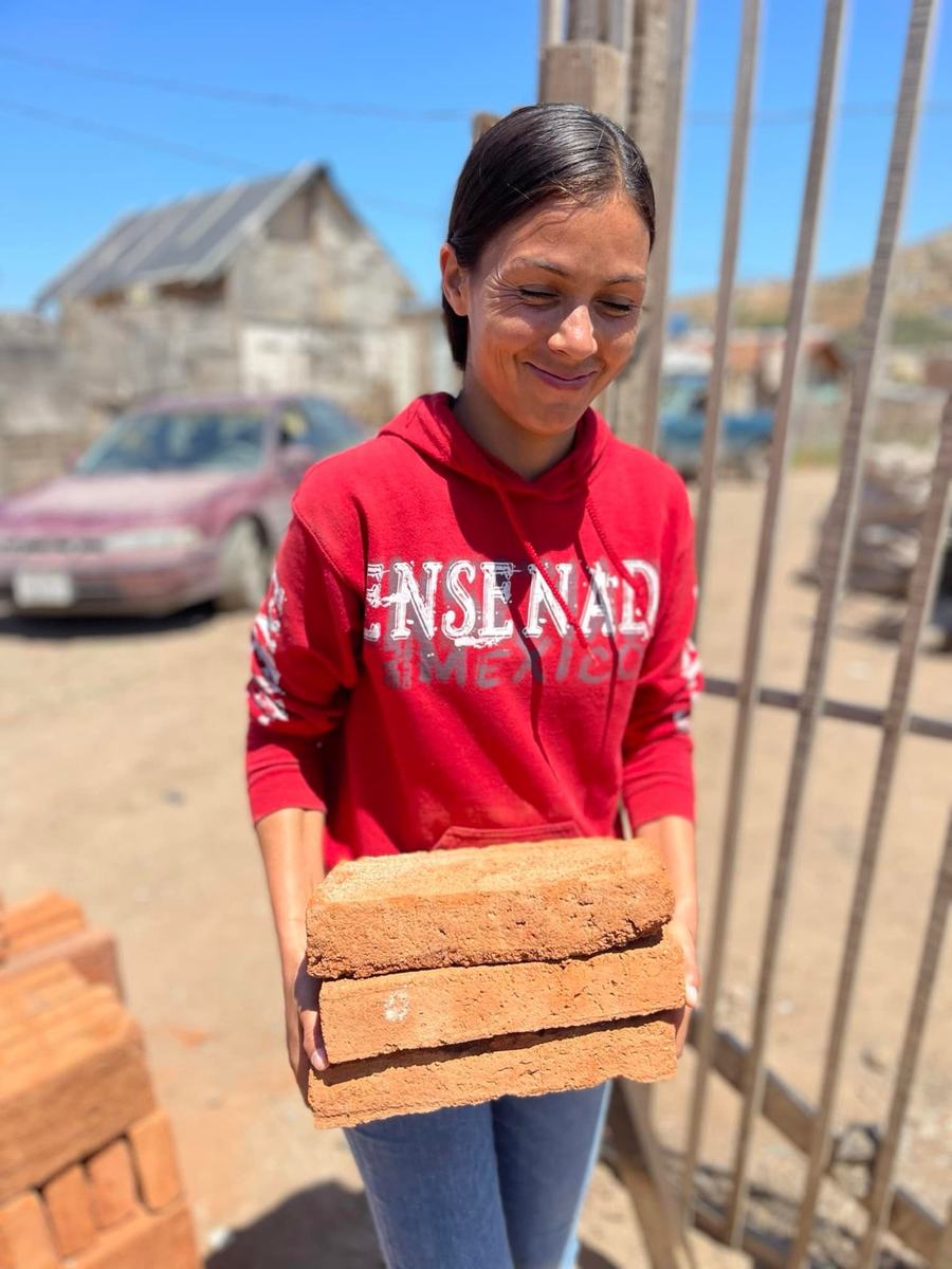 A woman in a red Ensenada sweatshirt carrying bricks