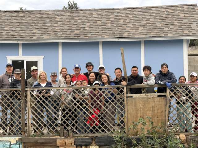 Volunteers and family gathered at a finished blue home