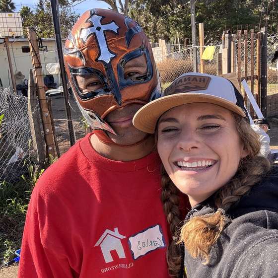 A boy in a lucha libre mask with a smiling volunteer