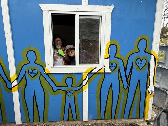 A family looking out the window of their mural-painted home