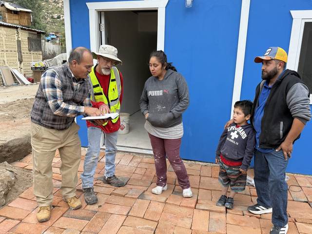 A family and volunteers at the door of a new blue home