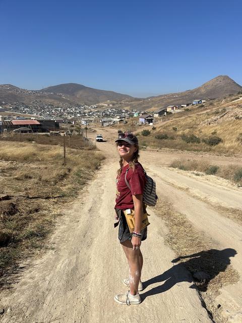 A volunteer walking a dusty road into the hills