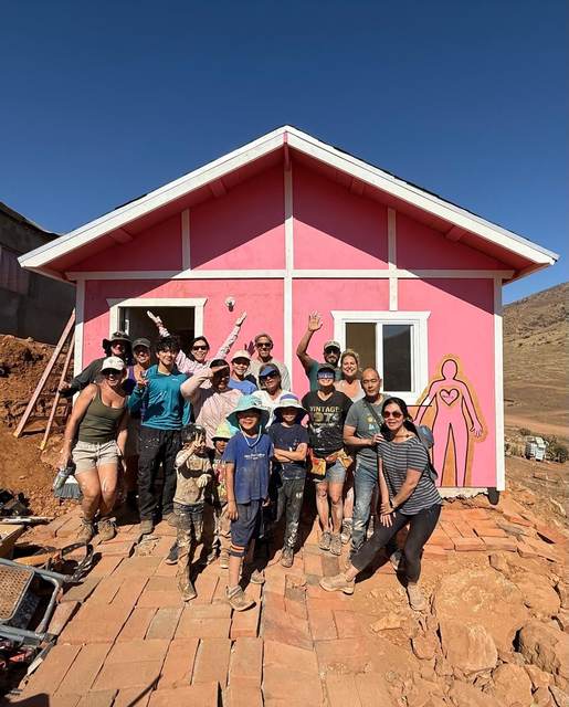 Volunteers waving in front of a pink home