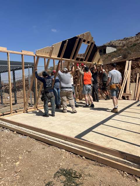 Volunteers raising a framed wall together